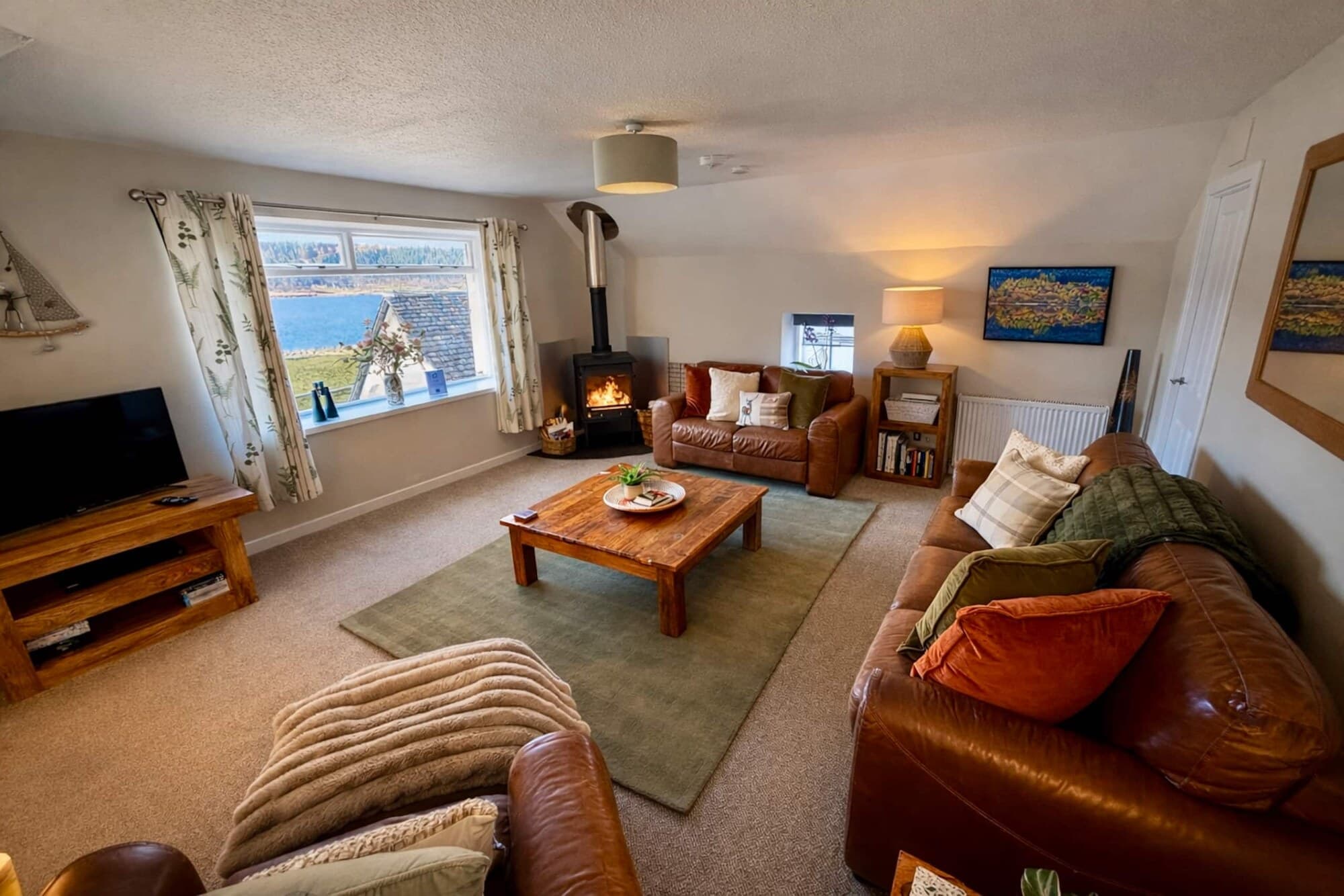 The open-plan sitting room, log burner lit, looking out over the loch